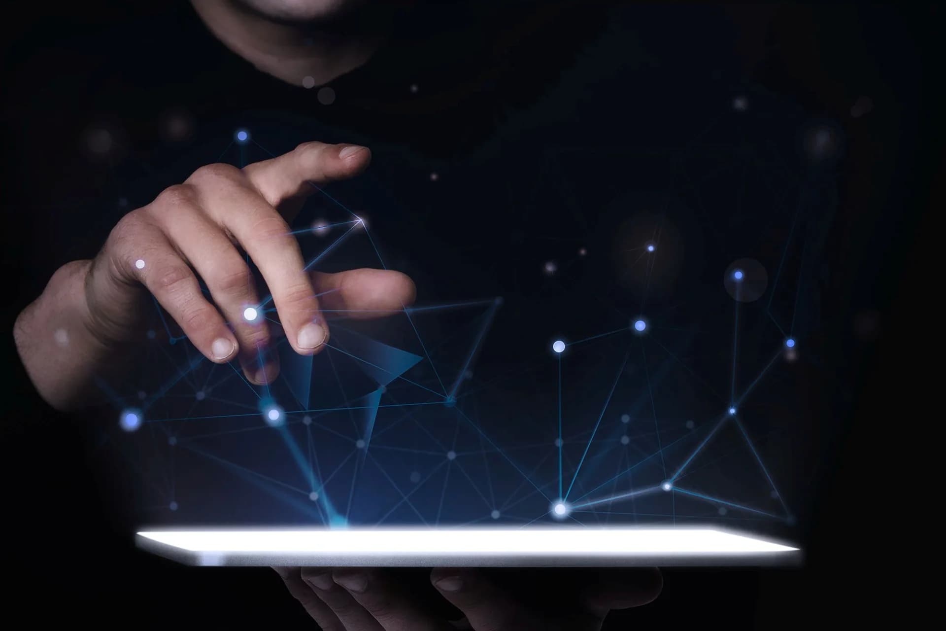 A hand touching a tablet surrounded by a glowing digital network