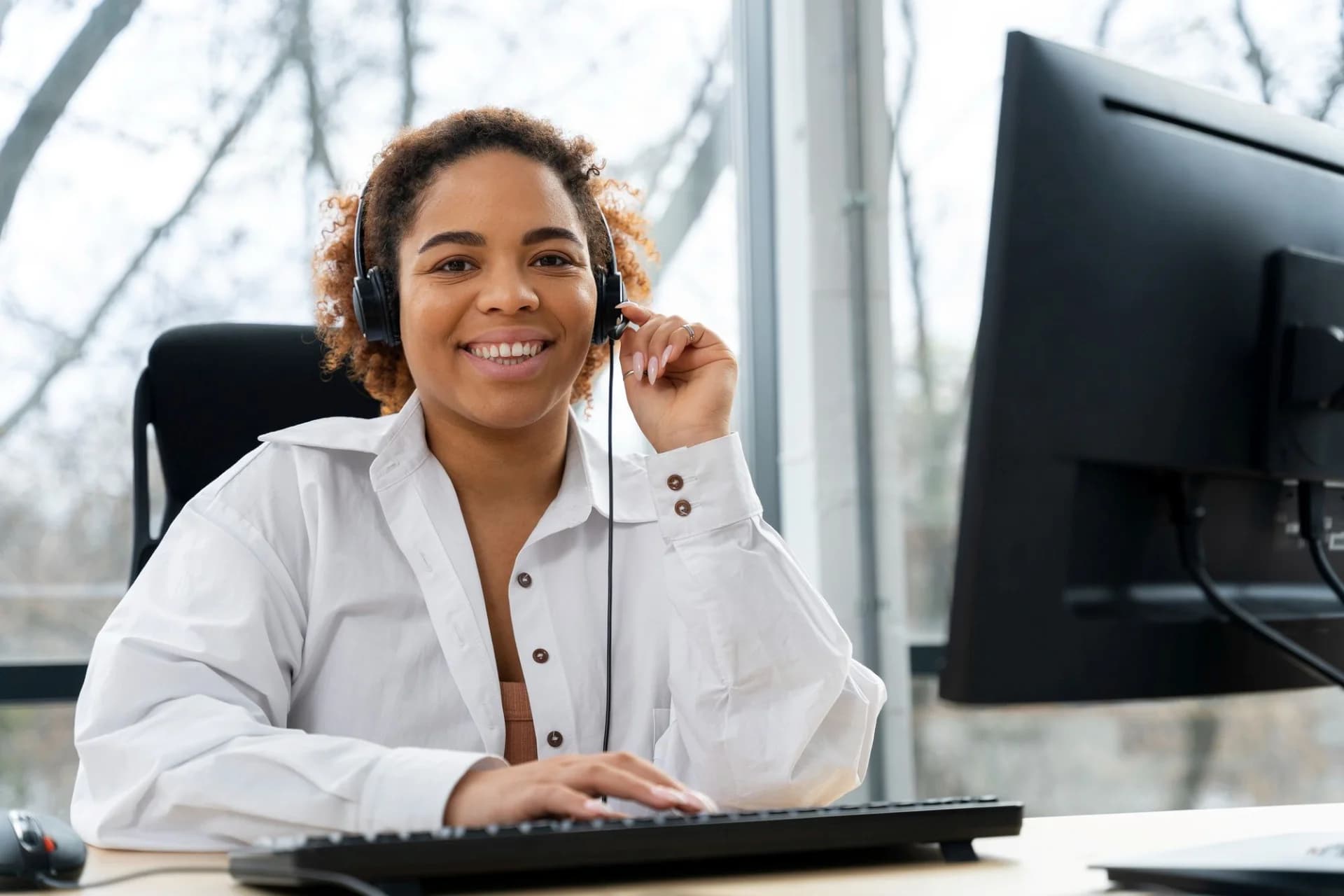 A smiling support advisor wearing a headset at a computer
