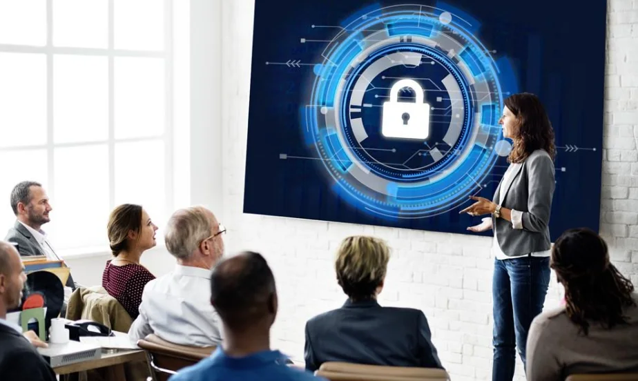 A presenter leading a cybersecurity awareness session in front of a screen showing a padlock